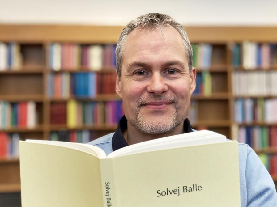 Bibliotekets litteraturformidler Anders holder Solvej Balles bog 'Om udregning af rumfang' op foran sig